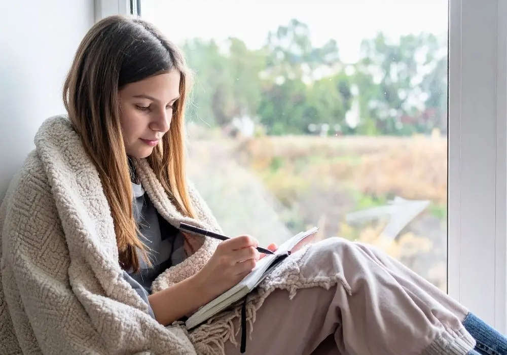 A reflective person writing in a notebook, representing counselling for feeling not good enough and self-worth in Vancouver